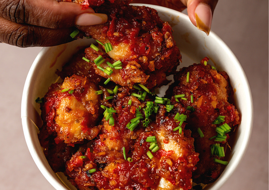 ATÀ ỌBÀ Heat Glazed Crispy Chicken wings in a bowl scattered with fresh chives