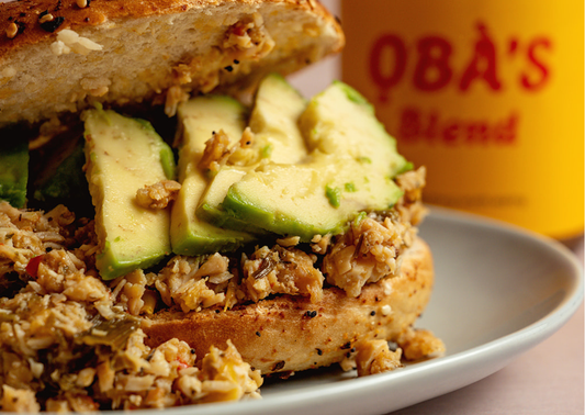 ỌBÀ’S BLEND avocado and grain bagel on a ceramic plate with the jar in the background